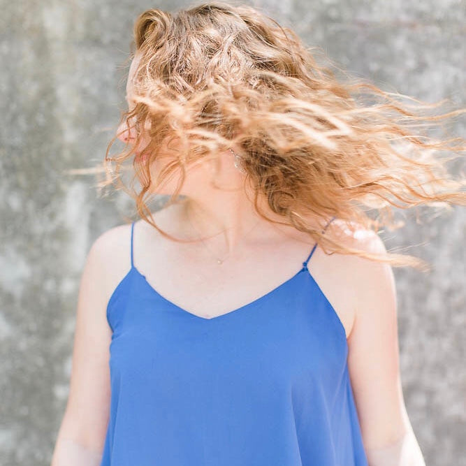 women in mid hair whip to the side wearing blue spaghetti strapped shirt
