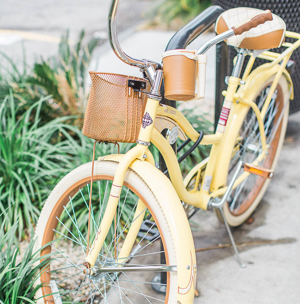 Yellow lindsey larue bicycle parked on the sidewalk beside ferns planted in ground
