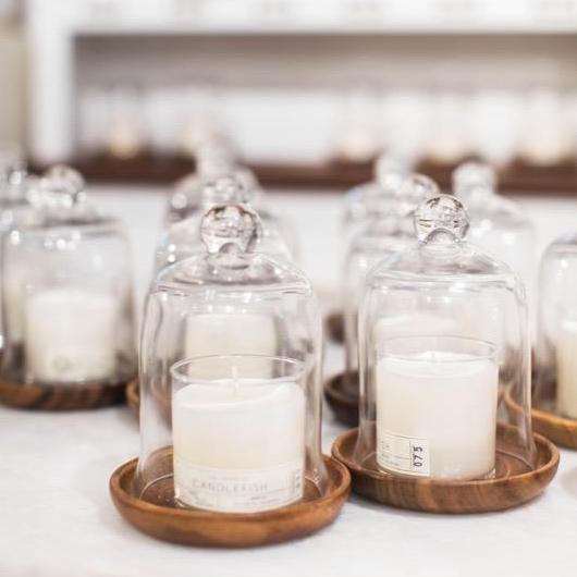 Small white candles on wooden plate with glass dome shaped tops