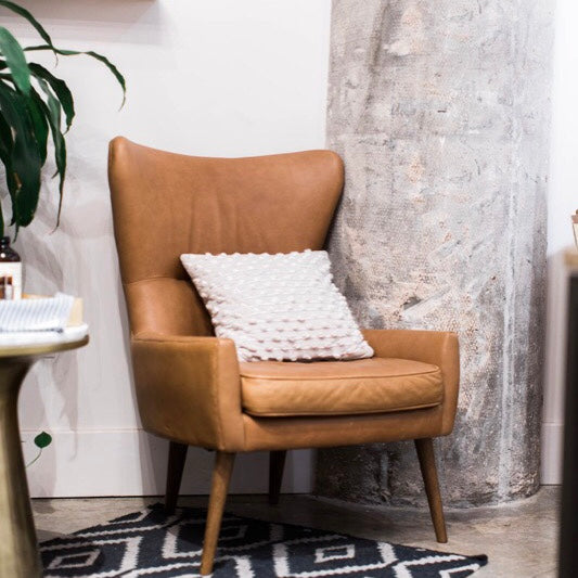 cool brown leather chair in corner of room with black and white designed carpet 