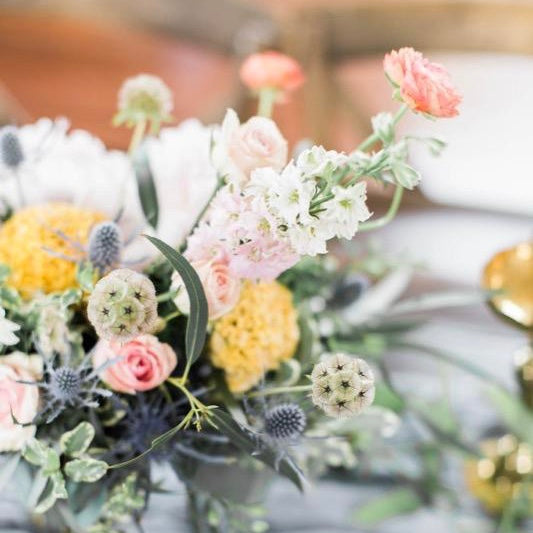 Small pink, yellow, white and light green flowers in a small skinny vase