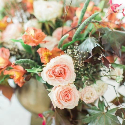 Light pink, orange flowers in copper vase