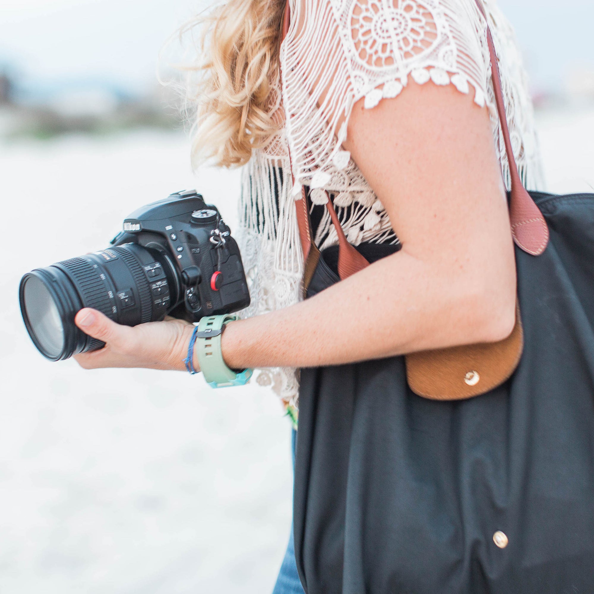 Woman holder a large bag on her shoulder and professional camera in hand